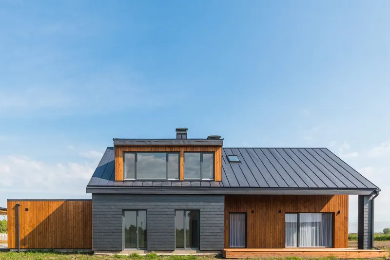 Dark timber and grey house with a steep roof against a clear sky