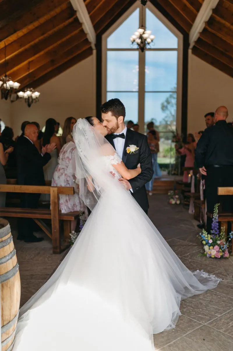 Bride and groom kissing inside a timber chapel, guests in the pews